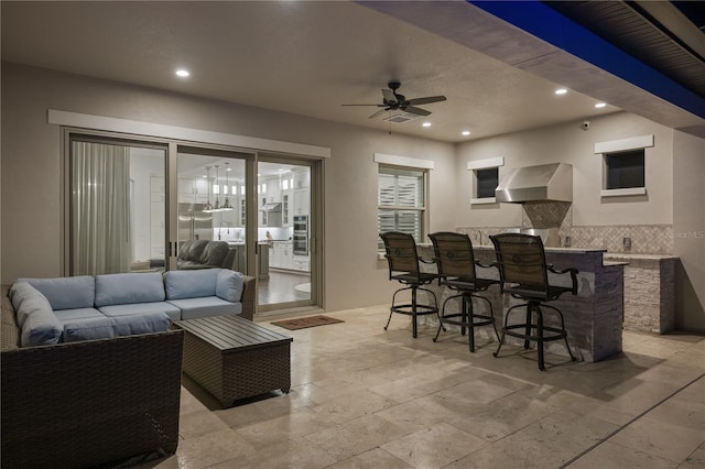 view of patio / terrace featuring a bar, ceiling fan, and an outdoor living space