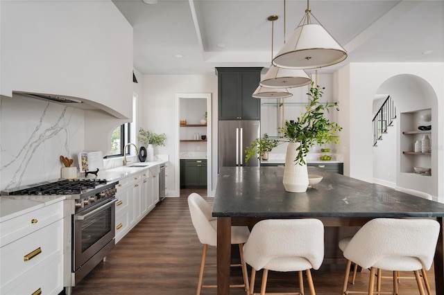 kitchen featuring sink, appliances with stainless steel finishes, dark hardwood / wood-style flooring, pendant lighting, and white cabinets