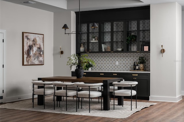 bar featuring hardwood / wood-style floors and decorative backsplash