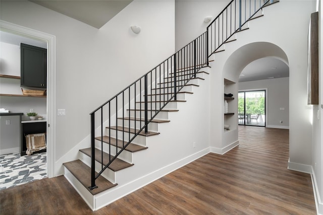 staircase with a high ceiling and wood-type flooring