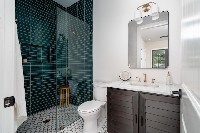 bathroom with vanity, tile patterned flooring, toilet, and tiled shower