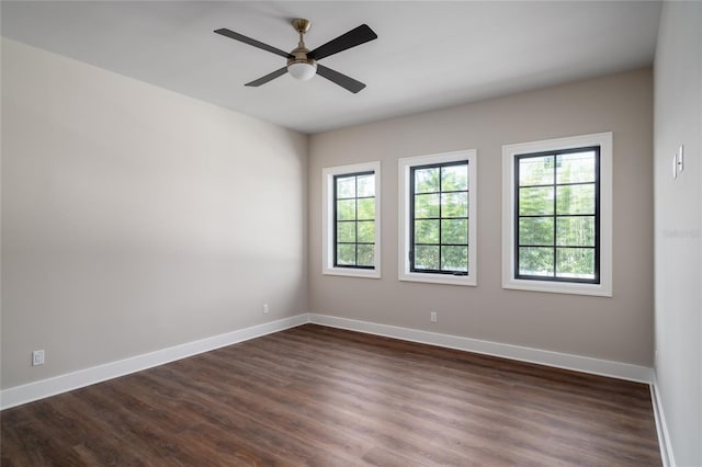 empty room with a healthy amount of sunlight, dark wood-type flooring, and ceiling fan