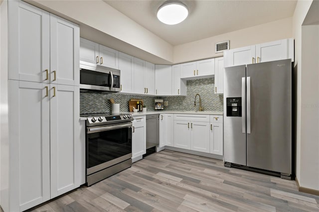 kitchen with tasteful backsplash, light countertops, visible vents, appliances with stainless steel finishes, and a sink