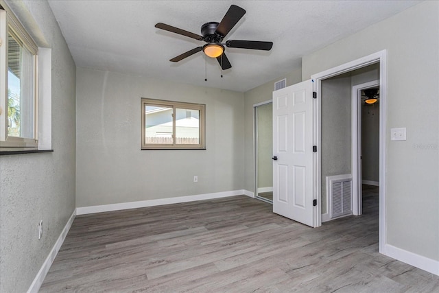 unfurnished bedroom with a textured ceiling, light hardwood / wood-style flooring, and ceiling fan