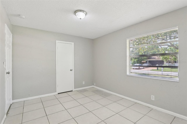 tiled empty room with a textured ceiling