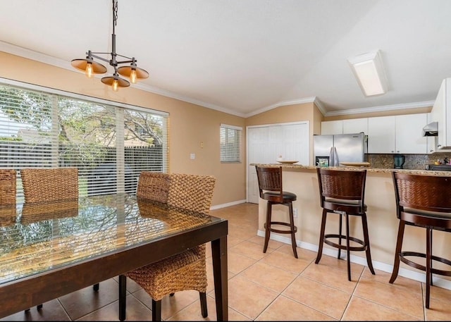 dining area with ornamental molding, lofted ceiling, light tile patterned floors, and a notable chandelier