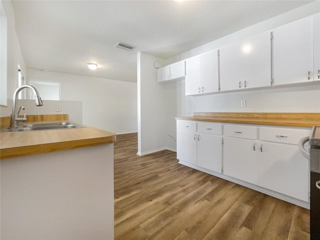 kitchen featuring hardwood / wood-style flooring, sink, white cabinets, and a textured ceiling