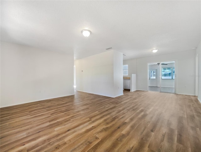 unfurnished living room featuring hardwood / wood-style flooring, ceiling fan, and a textured ceiling