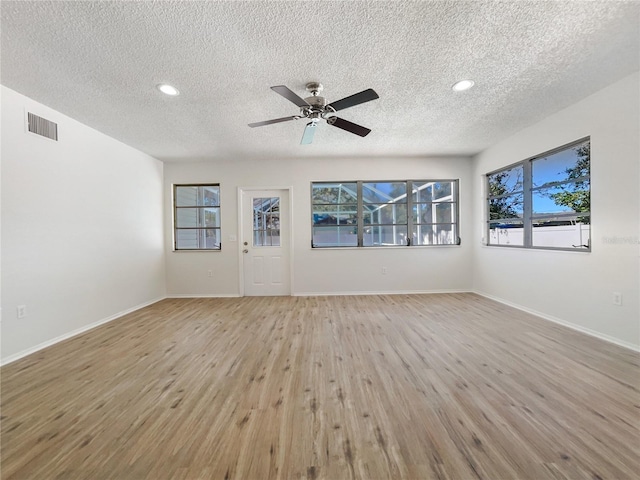 unfurnished living room featuring a textured ceiling, a wealth of natural light, ceiling fan, and light wood-type flooring