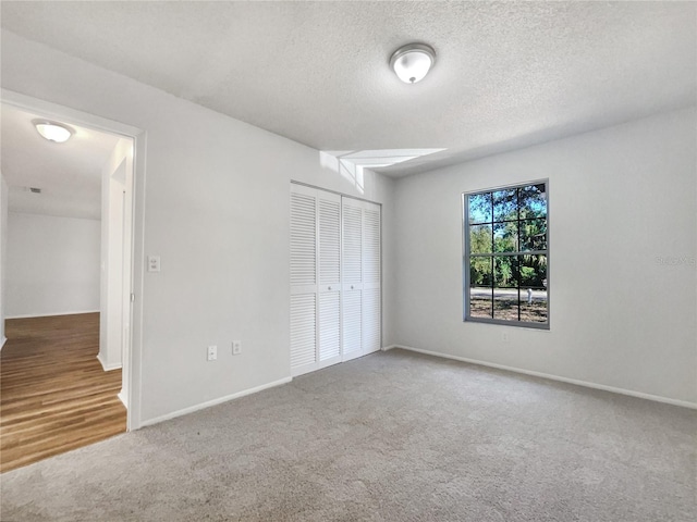 unfurnished bedroom with carpet flooring, a textured ceiling, and a closet