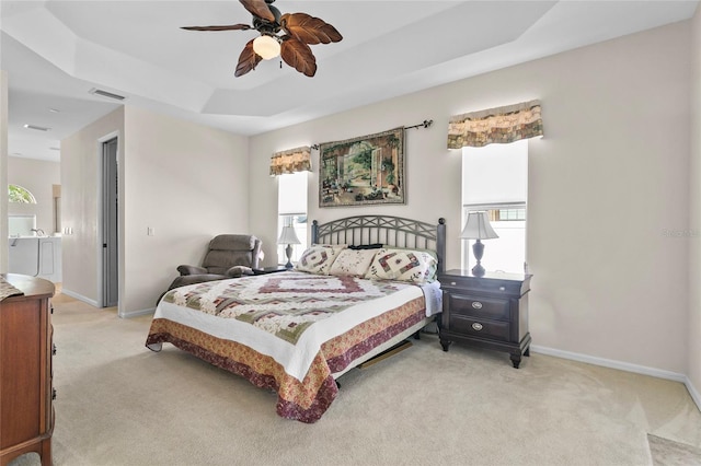 carpeted bedroom featuring ceiling fan and a tray ceiling