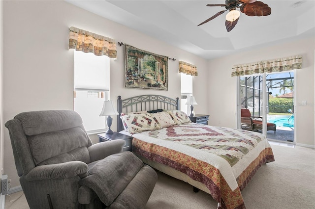 carpeted bedroom featuring a raised ceiling, access to exterior, and ceiling fan