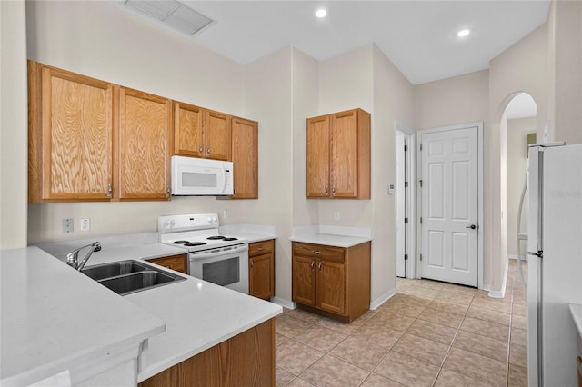 kitchen with white appliances, kitchen peninsula, sink, and light tile patterned floors