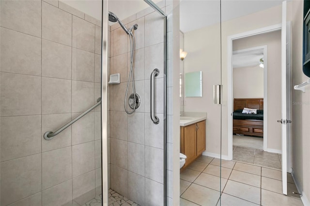 bathroom with a shower with door, ceiling fan, vanity, tile patterned floors, and toilet