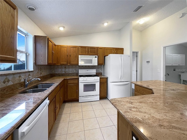 kitchen featuring sink, white appliances, vaulted ceiling, and light tile patterned floors