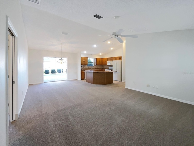 unfurnished living room featuring vaulted ceiling, ceiling fan with notable chandelier, and light carpet