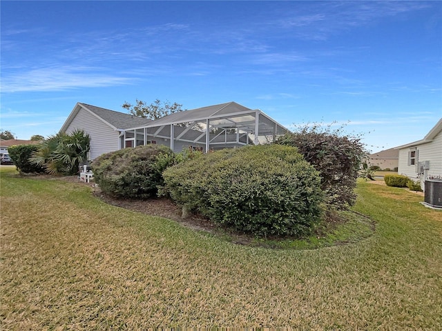 rear view of property featuring cooling unit, a yard, and a lanai