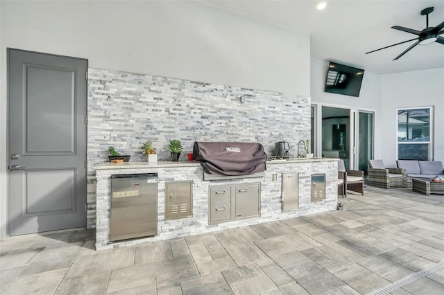 view of patio featuring a grill, ceiling fan, and an outdoor kitchen