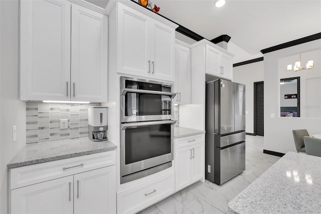 kitchen with stainless steel appliances, white cabinetry, light stone countertops, and decorative backsplash