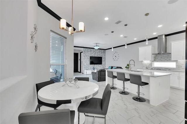 dining space with crown molding, sink, and a notable chandelier