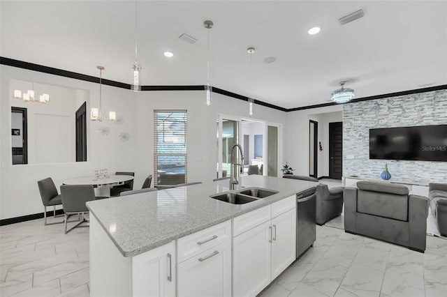 kitchen with sink, white cabinets, light stone counters, and decorative light fixtures