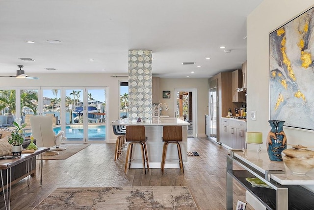 kitchen featuring ceiling fan, a breakfast bar area, stainless steel fridge, and light hardwood / wood-style floors