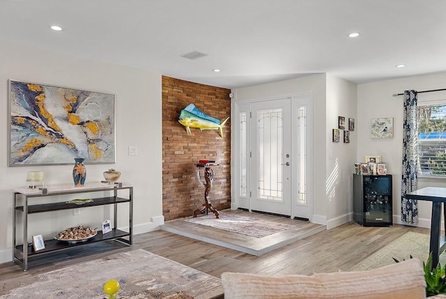 entryway with brick wall, beverage cooler, and light hardwood / wood-style floors