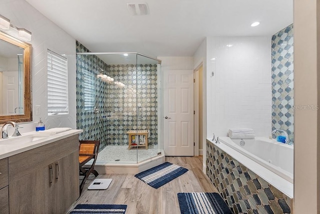 bathroom featuring hardwood / wood-style flooring, vanity, and shower with separate bathtub