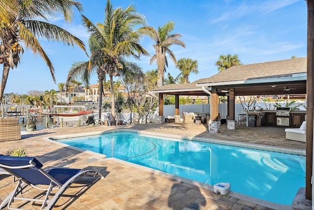 view of pool with a patio area, exterior kitchen, and a water view