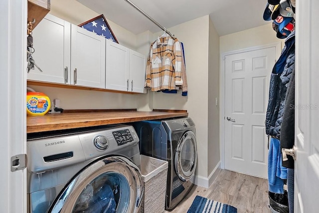 washroom featuring cabinets, independent washer and dryer, and light hardwood / wood-style floors