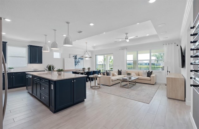 kitchen with a tray ceiling, light wood-type flooring, decorative light fixtures, and a kitchen island