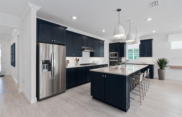 kitchen featuring a breakfast bar area, crown molding, hanging light fixtures, a center island with sink, and stainless steel appliances