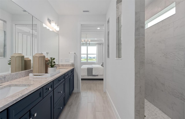 bathroom with vanity, a notable chandelier, and a tile shower