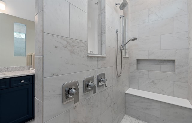 bathroom with a tile shower and vanity