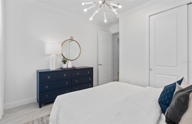 bedroom featuring a notable chandelier, crown molding, and light hardwood / wood-style floors