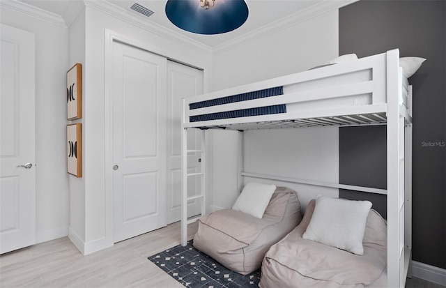 bedroom with crown molding, a closet, and light wood-type flooring