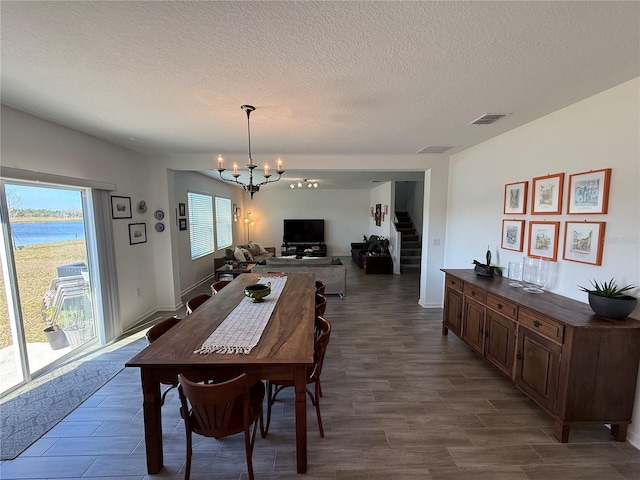 dining space with a water view, a wealth of natural light, dark wood-type flooring, and a notable chandelier