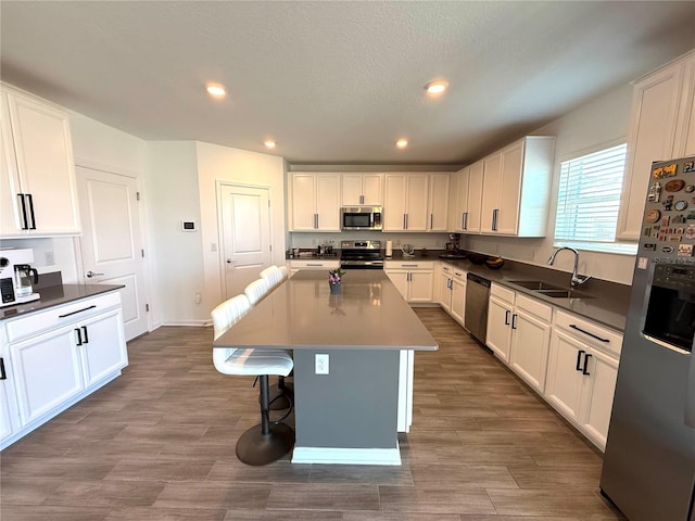 kitchen featuring white cabinetry, stainless steel appliances, a center island, and sink