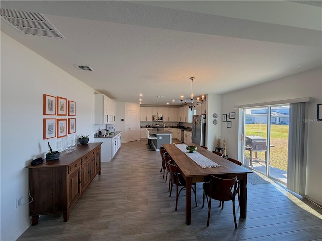 dining space featuring wood-type flooring, a textured ceiling, and an inviting chandelier