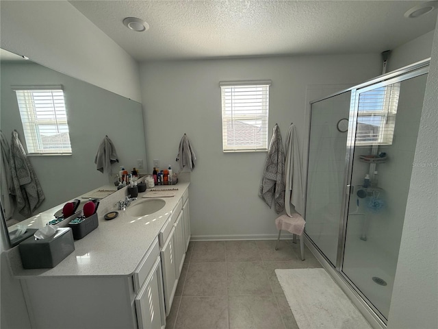 bathroom with tile patterned flooring, vanity, a textured ceiling, and walk in shower