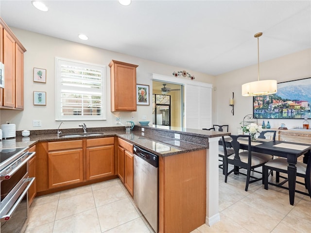 kitchen with pendant lighting, sink, appliances with stainless steel finishes, dark stone countertops, and kitchen peninsula