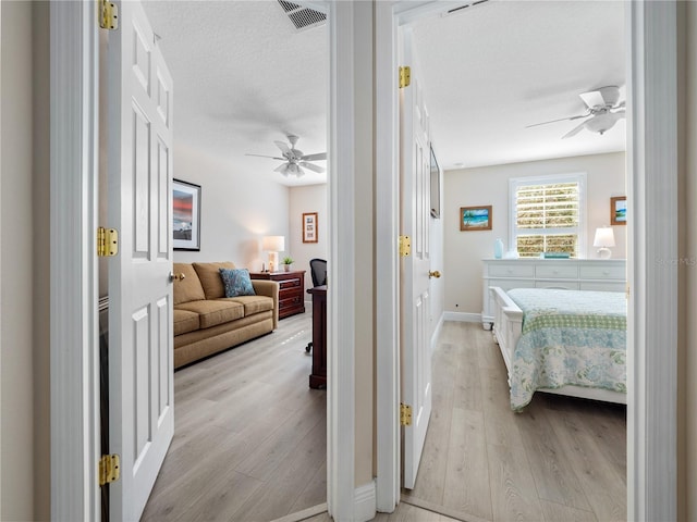 hallway featuring light hardwood / wood-style flooring and a textured ceiling