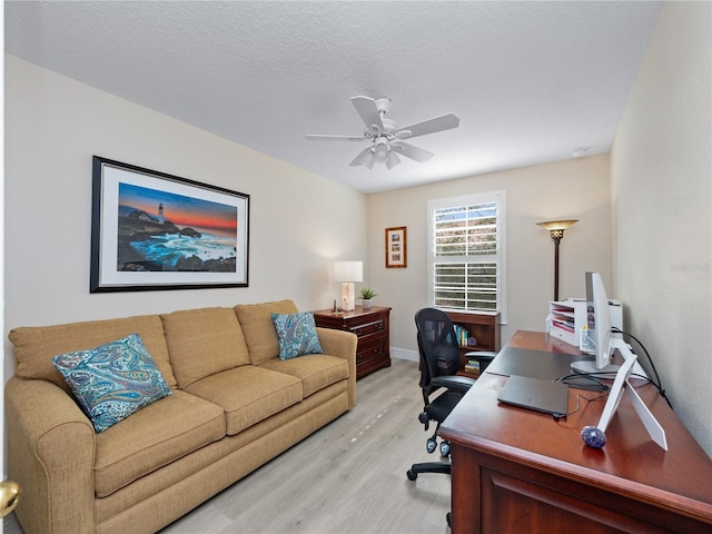 office featuring a textured ceiling, ceiling fan, and light wood-type flooring