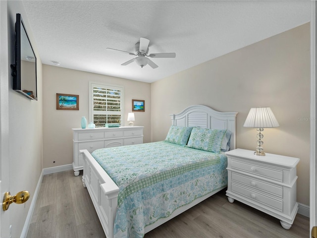 bedroom with hardwood / wood-style flooring, ceiling fan, and a textured ceiling