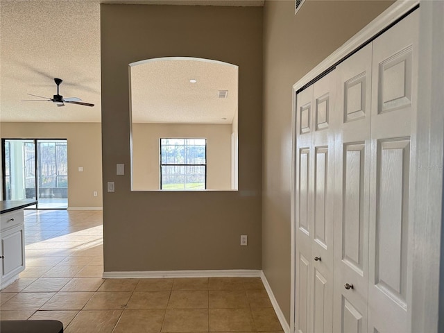 corridor featuring light tile patterned flooring and a textured ceiling