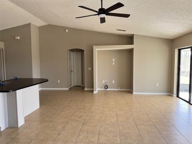 unfurnished living room featuring lofted ceiling, light tile patterned floors, a textured ceiling, and ceiling fan