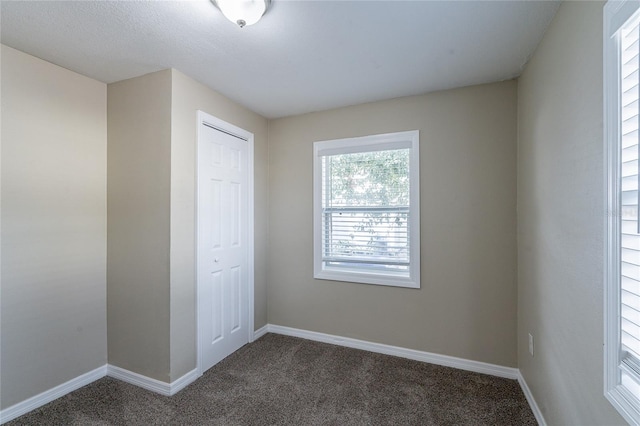 unfurnished room featuring dark colored carpet