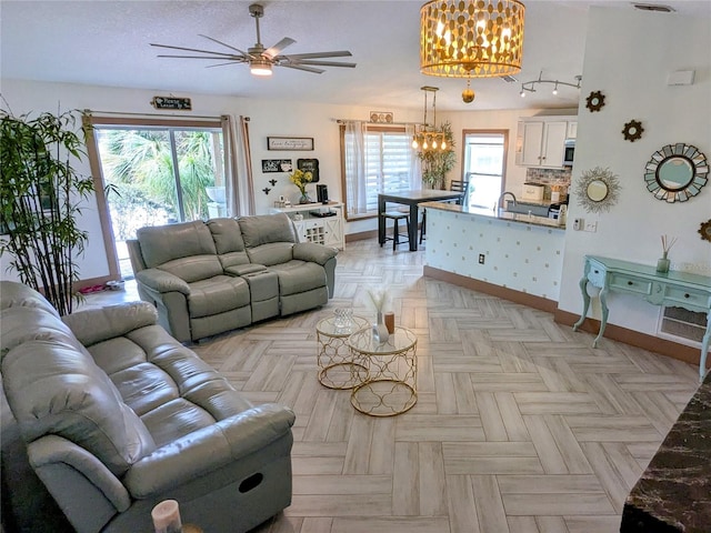 living room featuring sink, ceiling fan with notable chandelier, plenty of natural light, and light parquet flooring