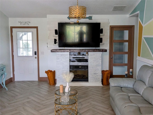 living room featuring a fireplace, a textured ceiling, and light parquet floors