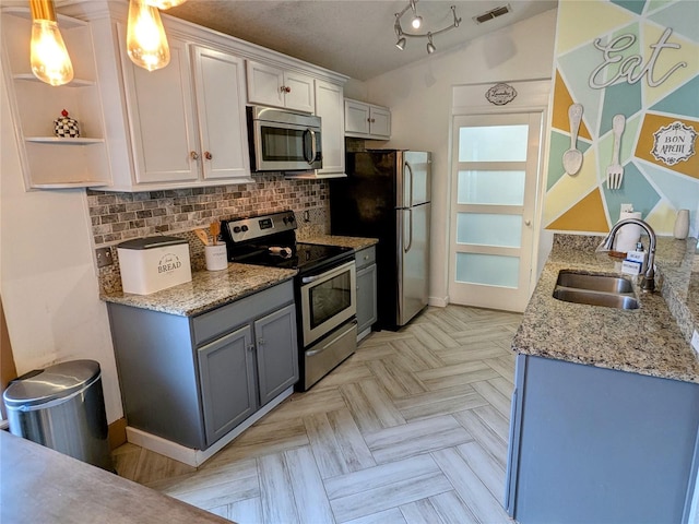 kitchen with sink, light parquet floors, hanging light fixtures, stainless steel appliances, and white cabinets